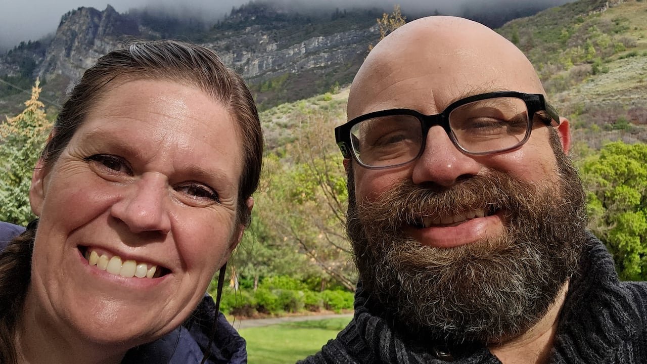 A man and woman smiling with mountains in the background