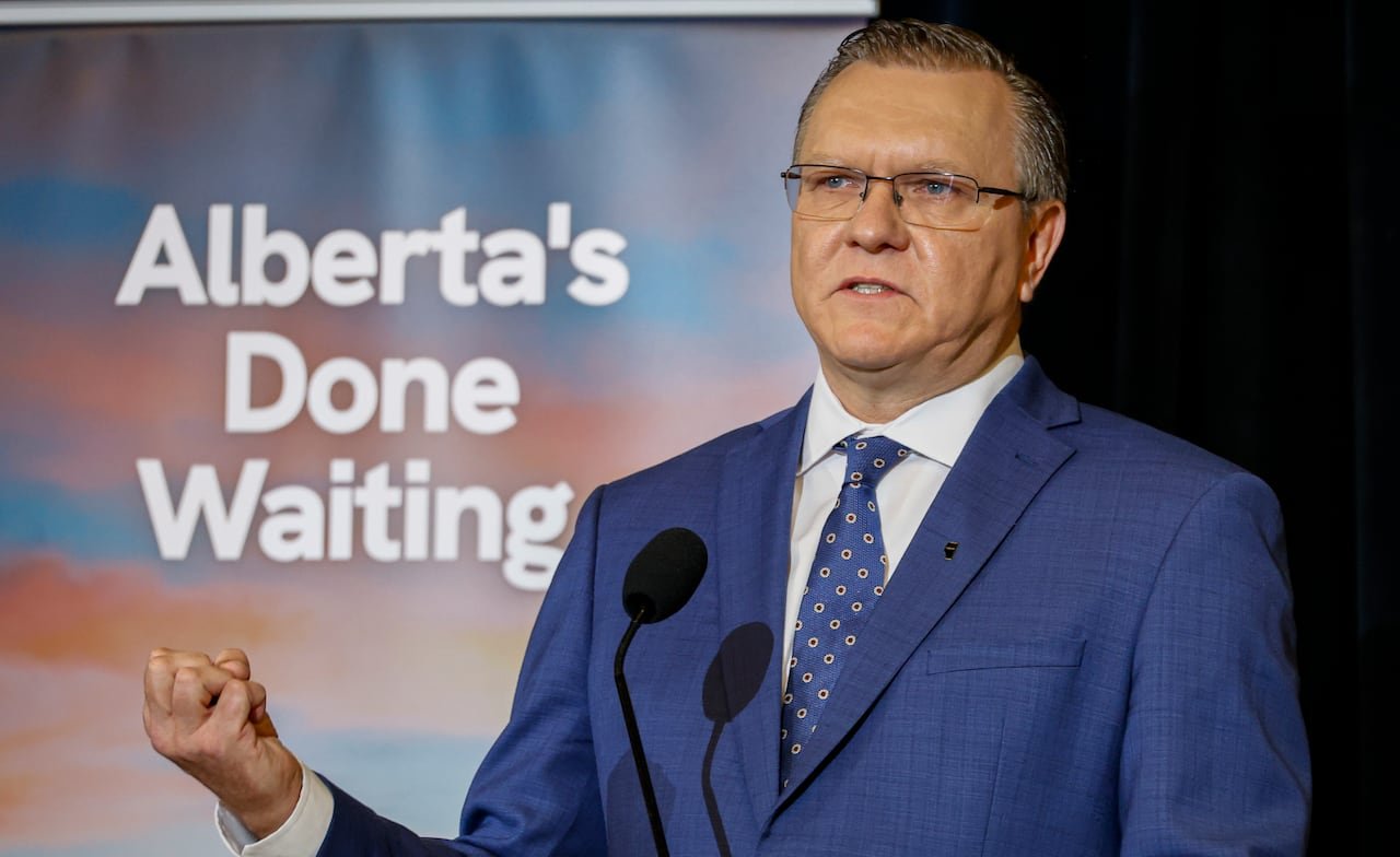 default-693 Person in blue suit and tie makes fist while speaking into microphone.