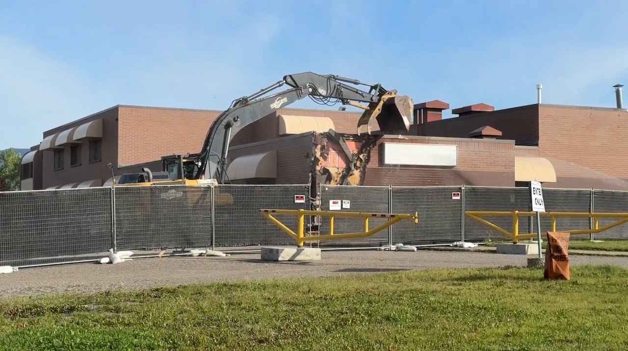default-7 An excavator is pictured tearing down the corner of a building, exposing bricks on its corner.
